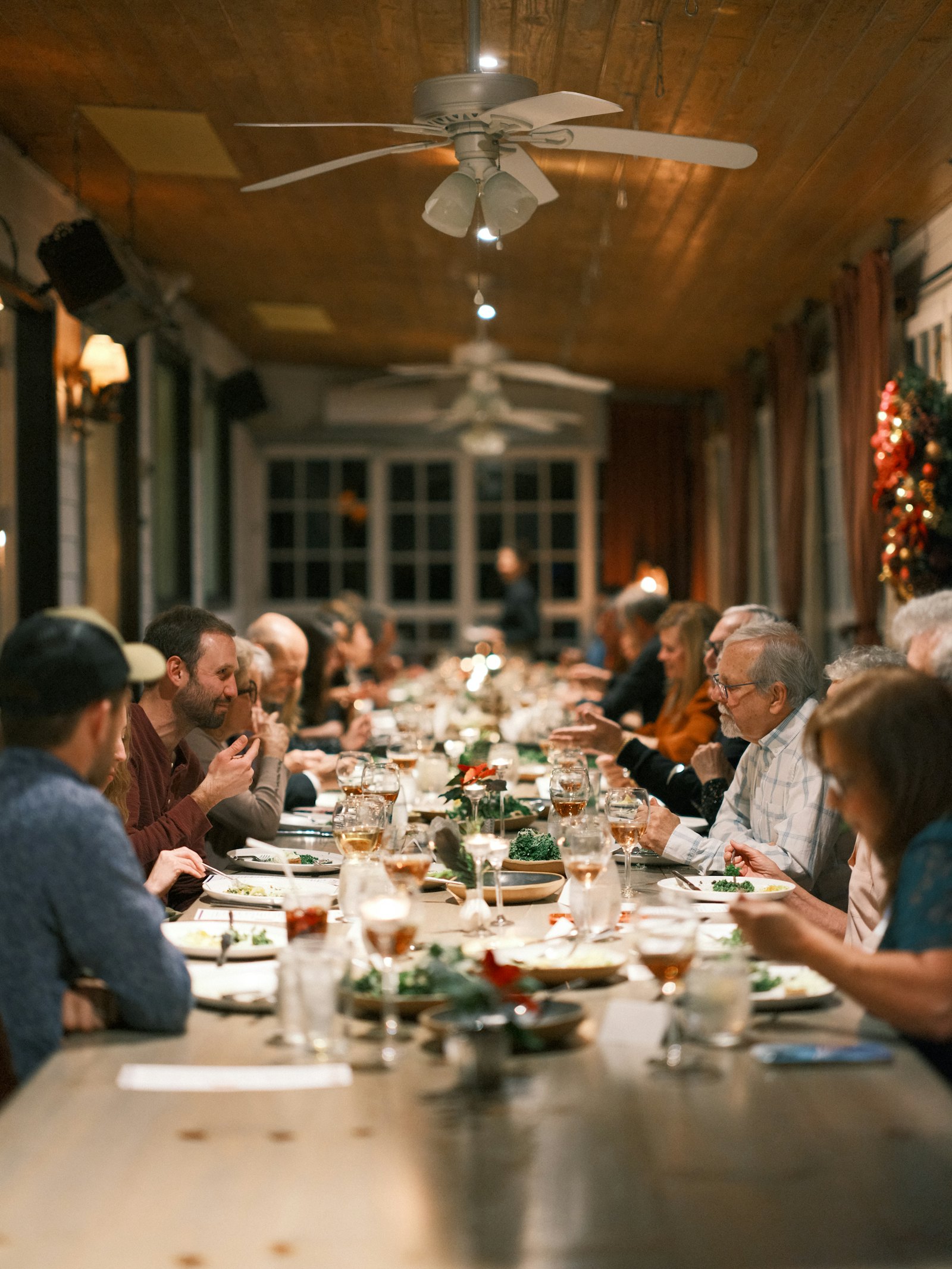 People sharing dinner and conversation along a community table