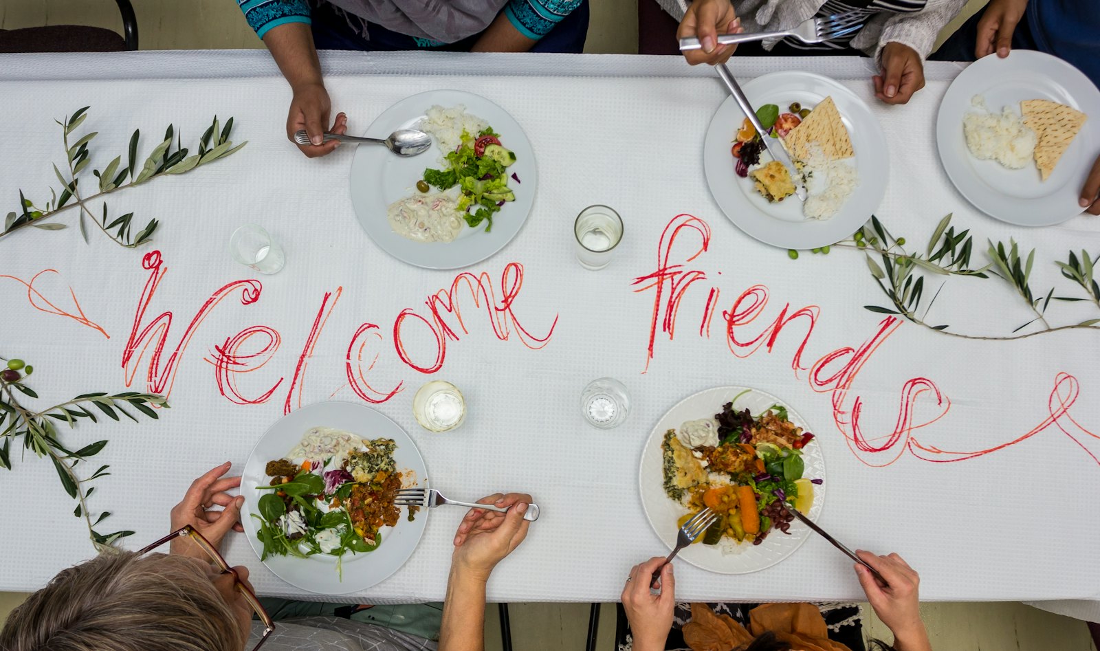 People sharing a meal around a table decorated with a welcome message