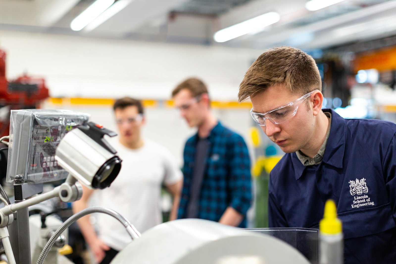 An engineering student working with machinery alongside other students